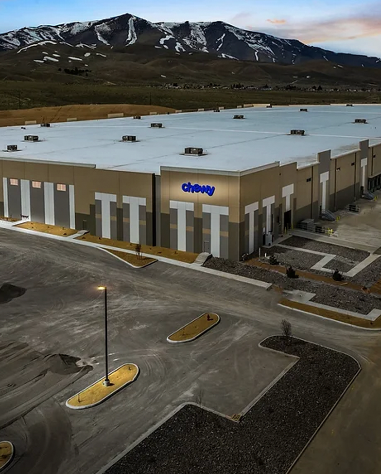 Aerial view of the Reno Logistics Center development that is currently fully leased by the company Chewy. Their dark blue logo is placed on the building with lighting behind it.